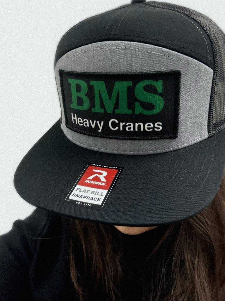 BMS Job-Site Series Trucker Hat worn, showcasing black, grey, and green colorway with structured front and mesh back for breathable comfort.